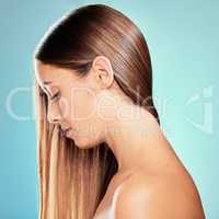 Sleek hair is her style. Studio shot of an attractive young woman posing against a blue background.