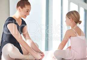 Ballet is like a rose. a ballet teacher and student stretching and talking on the floor of a dance studio.