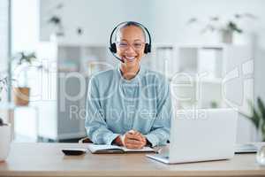 Happy and confident call center agent sitting in front of a laptop while wearing a headset in an office. Portrait of a cheerful saleswoman using web chat to assist customer sales and service support