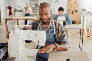 Fashion designer, young man and creative student in a workshop to sew clothes and garments. Factory worker, tailor and apprentice learning sewing machine skills in a textile and manufacturing studio