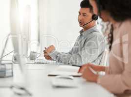 They are available to help you at any time. two young call center agents working in an office.