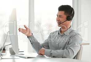 Everything seems to be in order. a young male call center agent using a computer in an office at work.