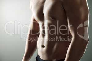 Guys with abs shouldnt be allowed to wear shirts. Studio shot of a muscular man posing against a grey background.