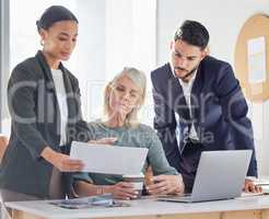 Analysing every detail to ensure precision in their plans. a group of businesspeople going through paperwork together in an office.