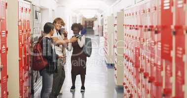 Friends make school extra fun. a group of teenagers using a smartphone in the corridor of a high school.