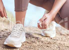 I have goals to accomplish today. Closeup shot of an unrecognisable woman tying her shoelaces while exercising outdoors.