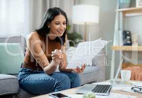 Im on the right track with my savings. an attractive young woman sitting alone in her living room at home and calculating her finances.