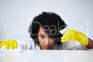 This counter will shine when im done. a young woman spraying down a counter to clean it.