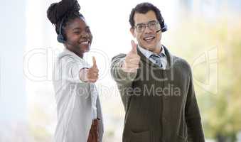 We guarantee the best in customer care. Portrait of two call centre agents showing thumbs up in an office.