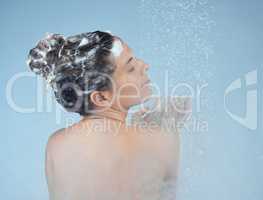 Use shampoo that is formulated for your hair type. Studio shot of an attractive young woman washing her hair while taking a shower against a blue background.