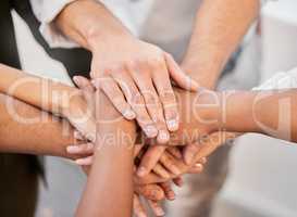 We can achieve everything together. an unrecognizable group of businesspeople huddled together in the office and piling their hands in the middle.