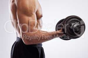 When form meets function. a man holding dumb bells against a studio background.