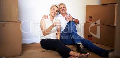 May your home be as happy as ours is. a mature couple toasting with water after a successful day moving house.