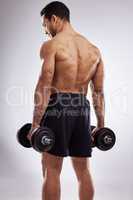 Dont neglect your back muscles. a man holding dumb bells against a studio background.