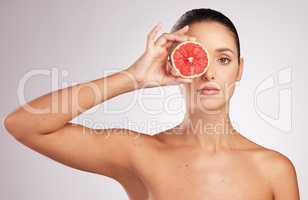Whats a skincare routine without vitamin c. an attractive young woman holding a grapefruit against a studio background.