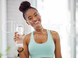 Stay hydrated. an attractive young woman standing alone and holding a bottle of water after practising yoga.