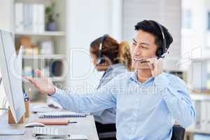 Happy, confident and helpful call centre agent talking on a headset while working on computer in an office. Salesman or consultant operating a help desk for customer care and service support