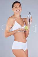 Junk food doesnt suit my lifestyle. Studio portrait of an attractive young woman eating a pear and drinking water against a grey background.