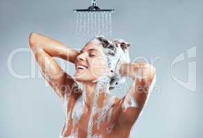 This is what makes me truly happy. a young woman washing her hair in the shower against a grey background.