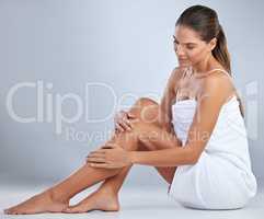 I love the feeling of smooth legs. Full length shot of an attractive young woman sitting alone and posing in her towel in the studio.