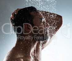 Life is incoherent, accept its flow. Studio shot of a young man washing his hair in a shower against a grey background.