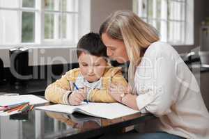 Dont worry honey just take your time. a mother and her son completing school work at home.