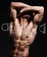 Hit the gym and do it hard. a muscular young man posing against a black background.