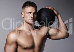 I want you to reach your fitness goals. a sporty young man holding an exercise ball while standing against a grey background.