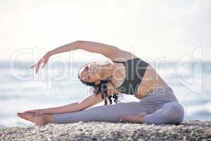 Feeling those yoga vibes. a young woman practising yoga on the beach.