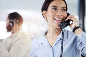 Leave it to me. an attractive young call centre agent sitting with her colleague in the office and using a telephone.
