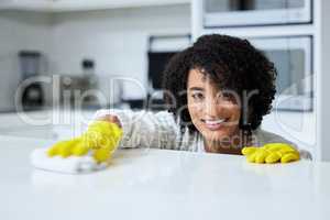 Spend a day spring cleaning. a young woman cleaning her kitchen counter.