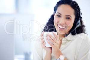 Im fuelling up for a very productive day. Portrait of a young call centre agent drinking coffee while working in an office.