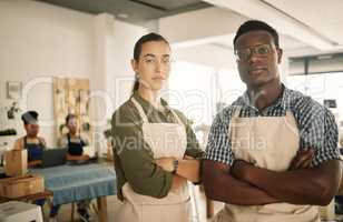 Fashion, design and style with two diverse and professional team members standing arms crossed and working in a creative workshop. Serious and confident textile workers in a small business startup