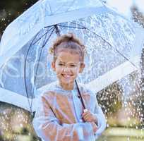 Always determined to have fun. a little girl playfully standing in the rain holding her umbrella.