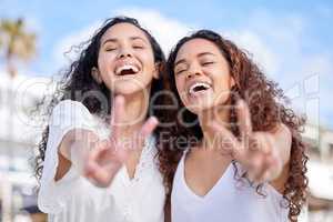 Heres to more good times together. two young women making peace gestures during a fun day outdoors.