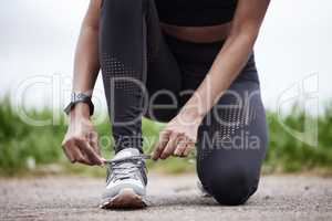 Ready to give it her all. Closeup shot of an unrecognisable woman tying her shoelaces while exercising outdoors.