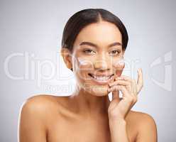 Reaping the benefits of a hydration boost. Studio shot of an attractive young woman applying moisturiser to her face against a grey background.