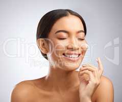 So good it feels like Im in a spa. Studio shot of an attractive young woman applying moisturiser to her face against a grey background.