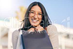 Retail therapy is a quick fix for any situation. Portrait of an attractive young woman walking alone outside while shopping in the city.