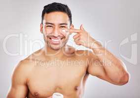 If self-care equates femininity, call me Miss. Studio portrait of a young man applying moisturiser to his face against a grey background.