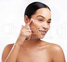 Moisturising reduces the chances of skin problems. Studio shot of a beautiful young woman applying moisturiser to her face against a white background.