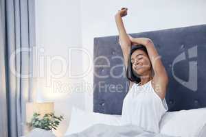 Theres nothing I love more than my sleep. a young woman stretching while sitting on her bed.