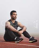 Wondering what my athletic future holds. a young male athlete sitting on the track before a race.