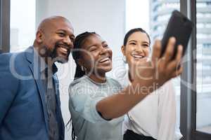 Confidence shines through them all. a group of businesspeople taking selfies together in an office.