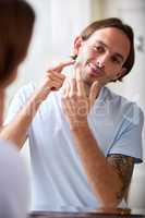 I think i might have gotten a pimple. a young man assessing his skin in the bathroom mirror.