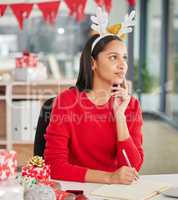 All I want for Christmas is a seaside vacation. a young businesswoman making notes in a modern office at Christmas.