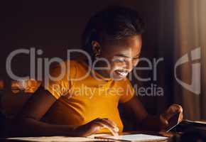 Happy, smiling woman paying bills, loans and shopping online on her tablet in the late evening at home. Single African American female downloading dating apps and making payment