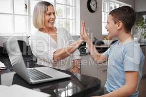 We make a great team. a young mother and her son high fiving while home schooling.