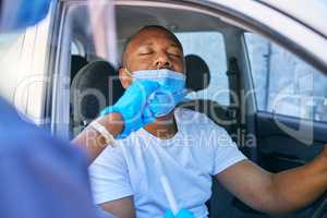 Covid testing and screening of a man driving in his car at a drive through station with medical nurse assistance. Guy getting virus treatment test while wearing a protective face mask