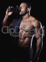 Feel it on your lips. Studio shot of a young fit man drinking water after exercising against a black background.